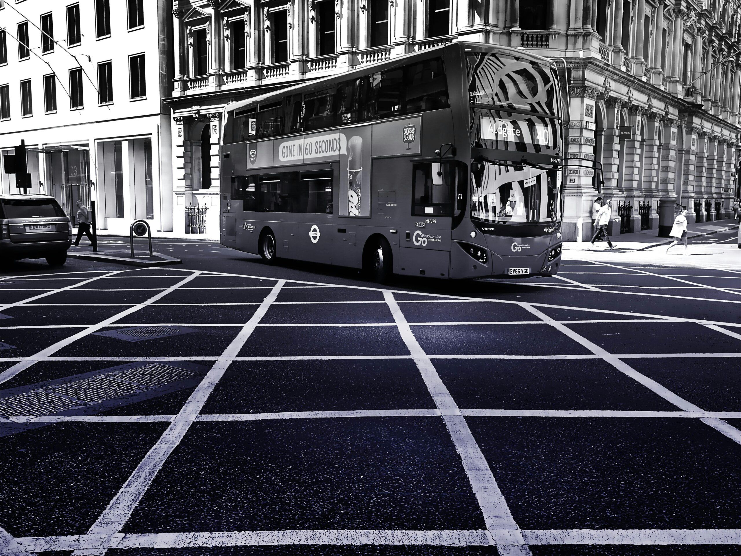 Monochrome image of a double-decker bus on London's urban streets, showcasing transportation and city life.