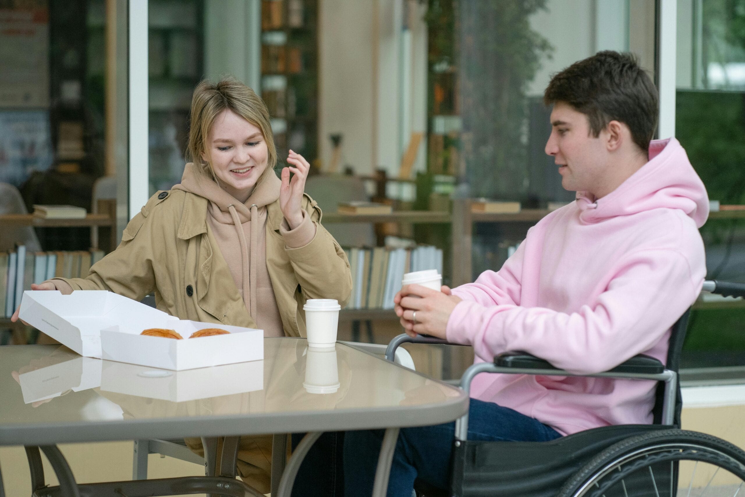 A couple sitting at an outdoor café table enjoying coffee and pastries in a relaxed setting.