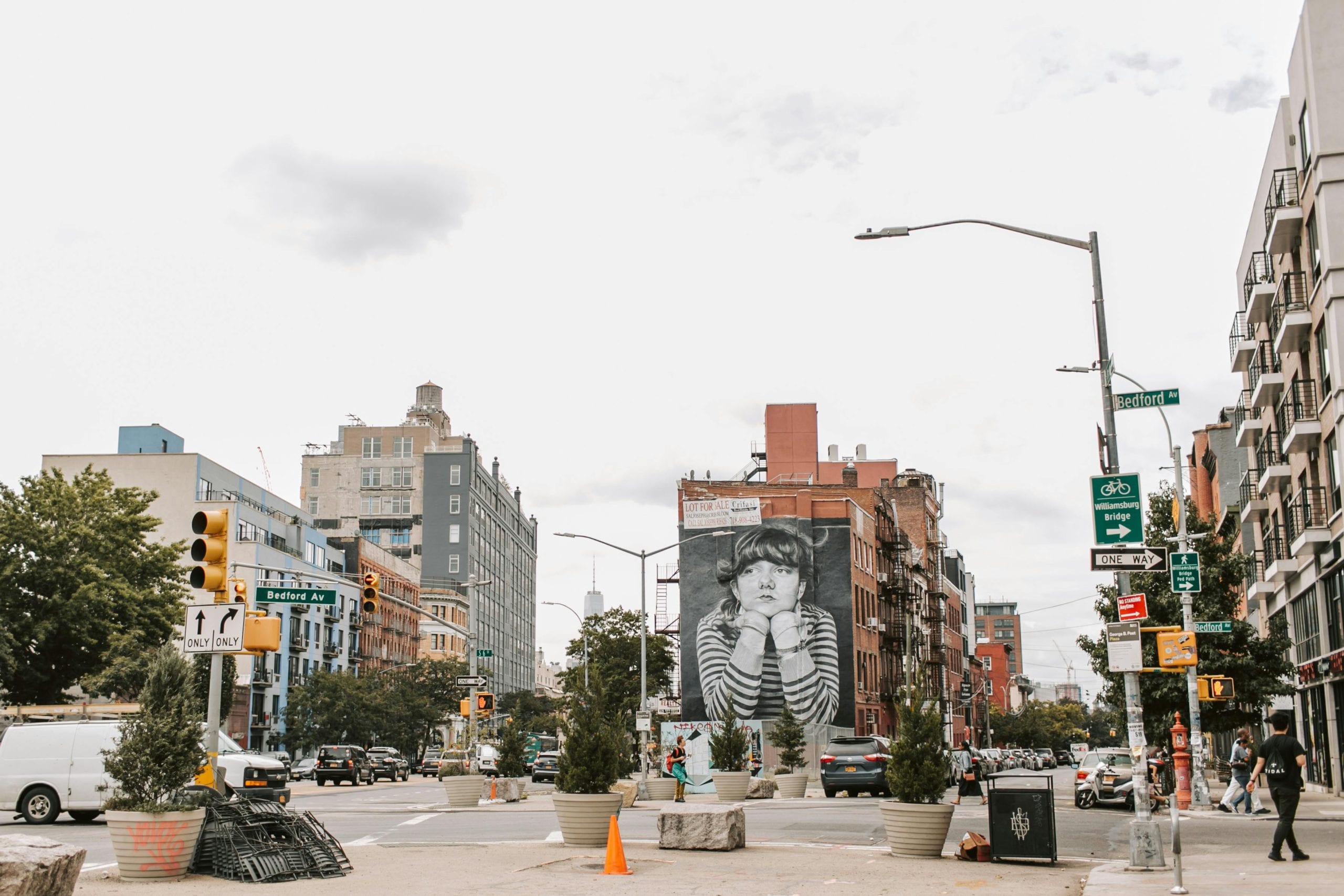 Vibrant street view of Bedford Avenue with famous mural and urban traffic in NYC.