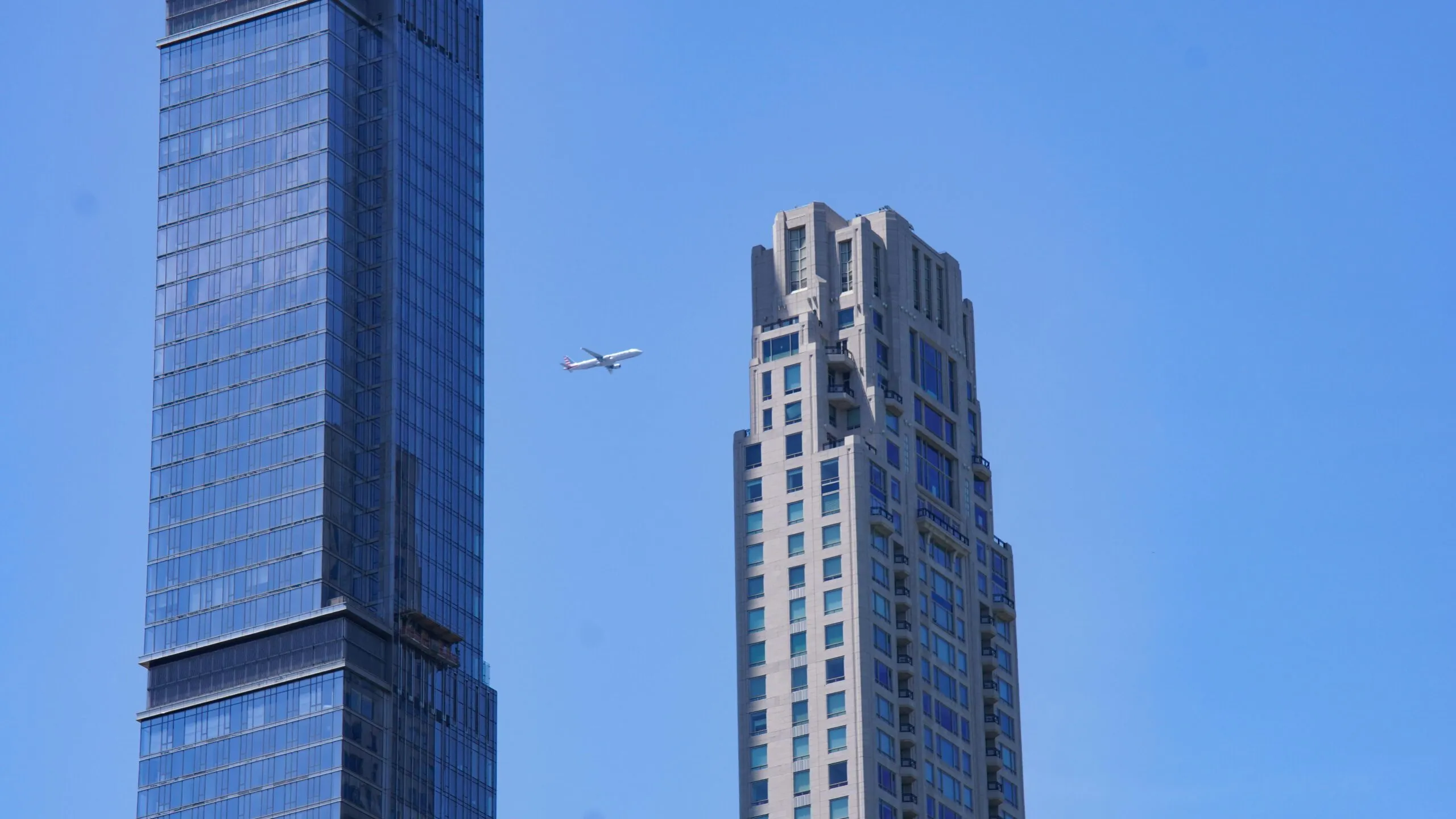 An airplane flying between two towering skyscrapers in Manhattan, New York City.