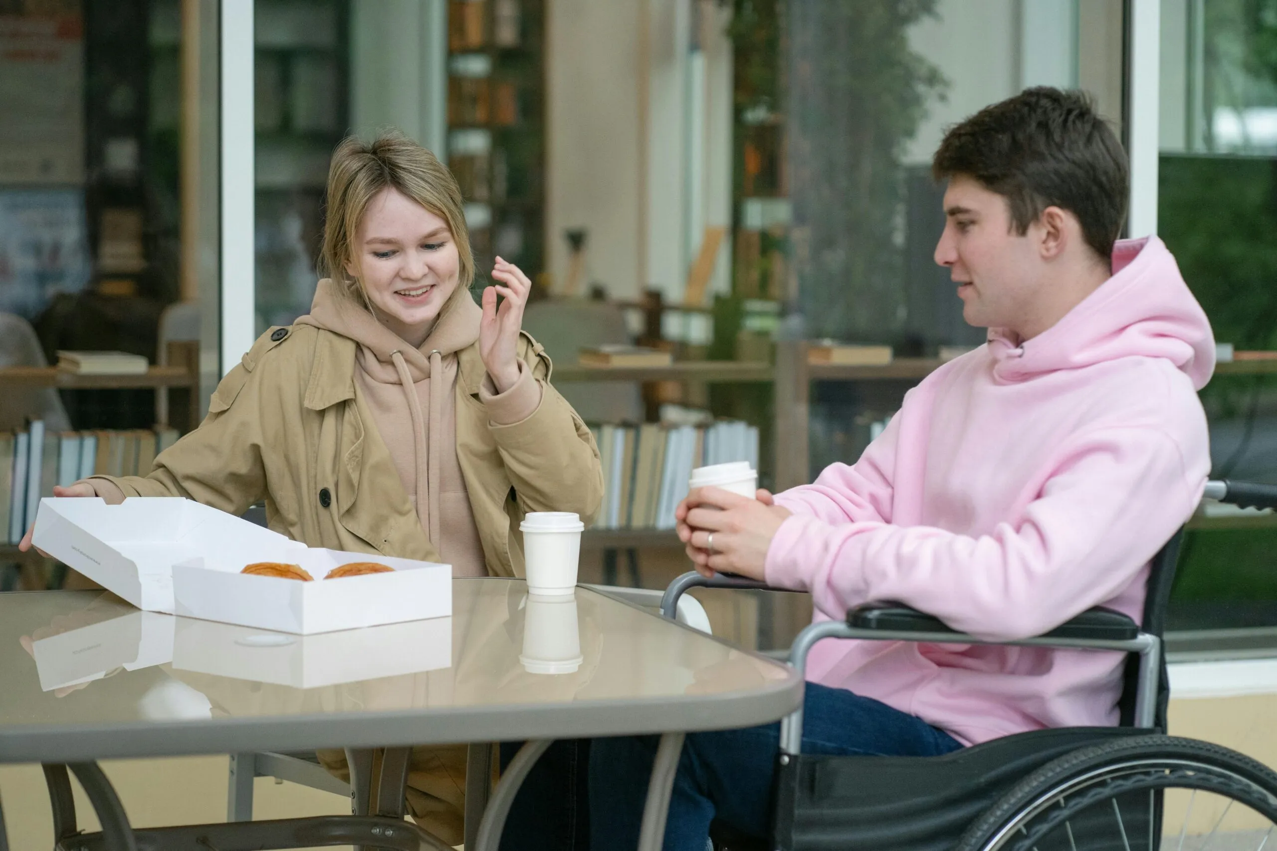 A couple sitting at an outdoor café table enjoying coffee and pastries in a relaxed setting.